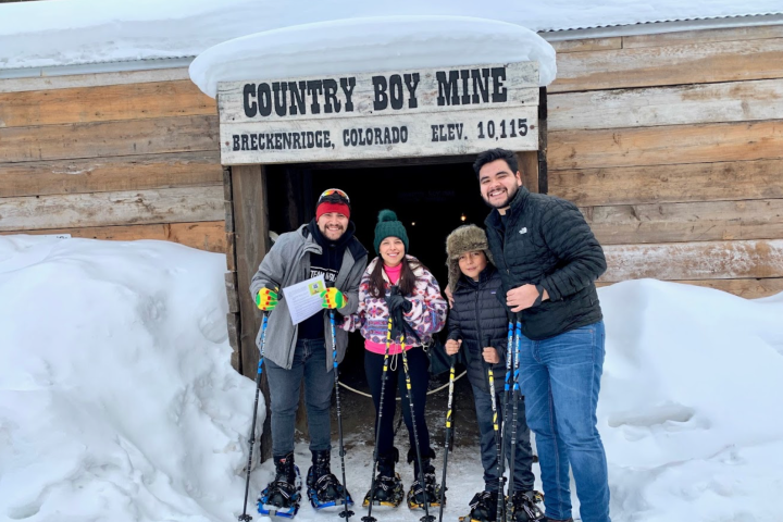 Four people in snowshoes smiling in front of Country Boy Mine entrance.