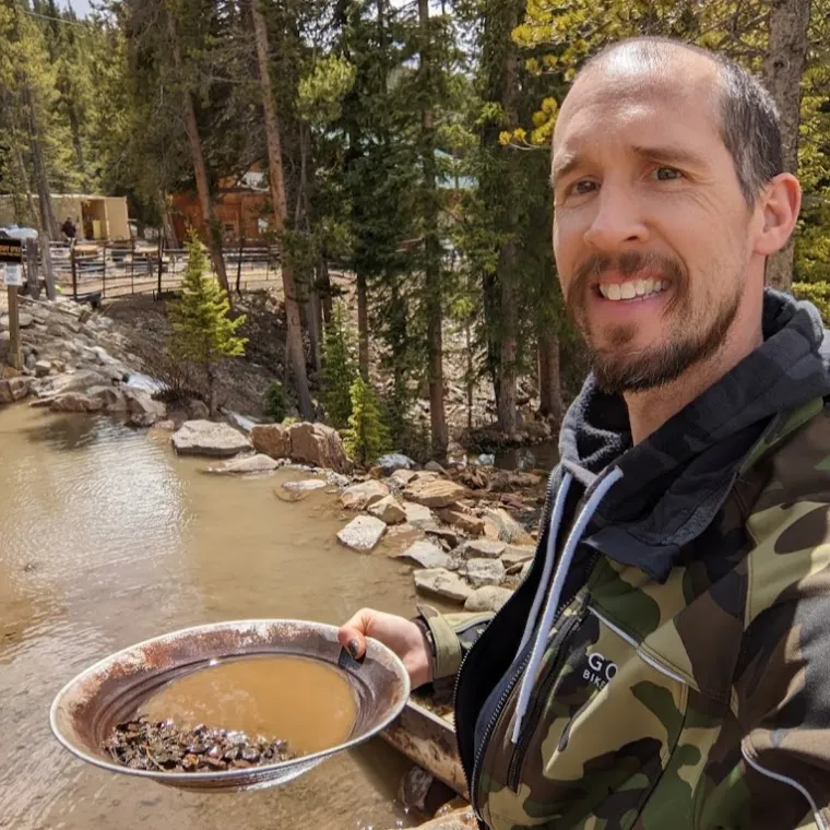 a man smiling for the camera while gold panning with country boy mine in breckenridge, colorado